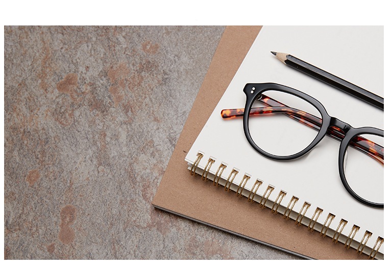 Round glasses #4432921 sit next to a black pencil atop a spiral bound notebook on a quartz background.