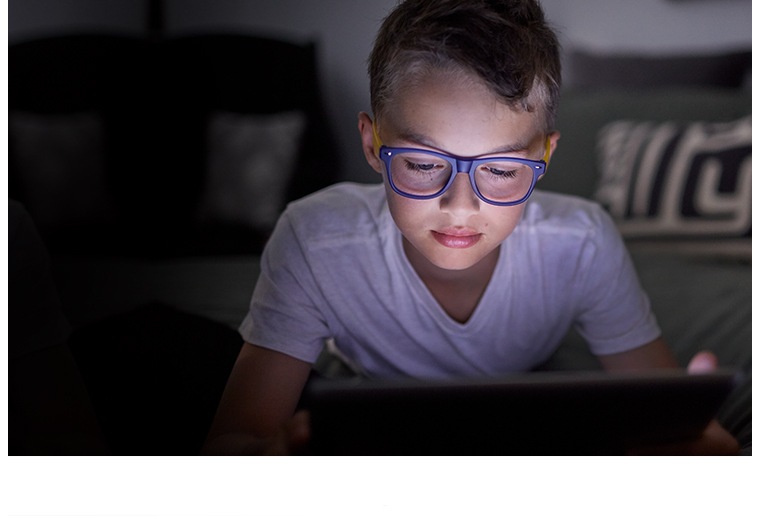 Young boy wearing Zenni Blokz Blue Blocking glasses, using a tablet.