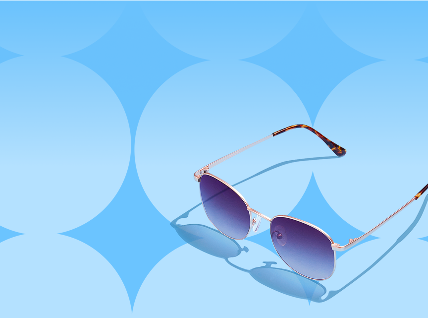 Round gold sunglasses with blue lenses and tortoiseshell temple arm tips on a blue patterned background.