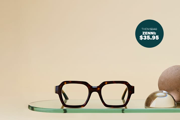 Thick-rimmed square tortoiseshell glasses, resting on a glass shelf on a beige background.