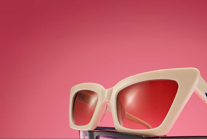 Bold, Zenni oversized cat-eye cream frames stacked against a gradient dark pink background.