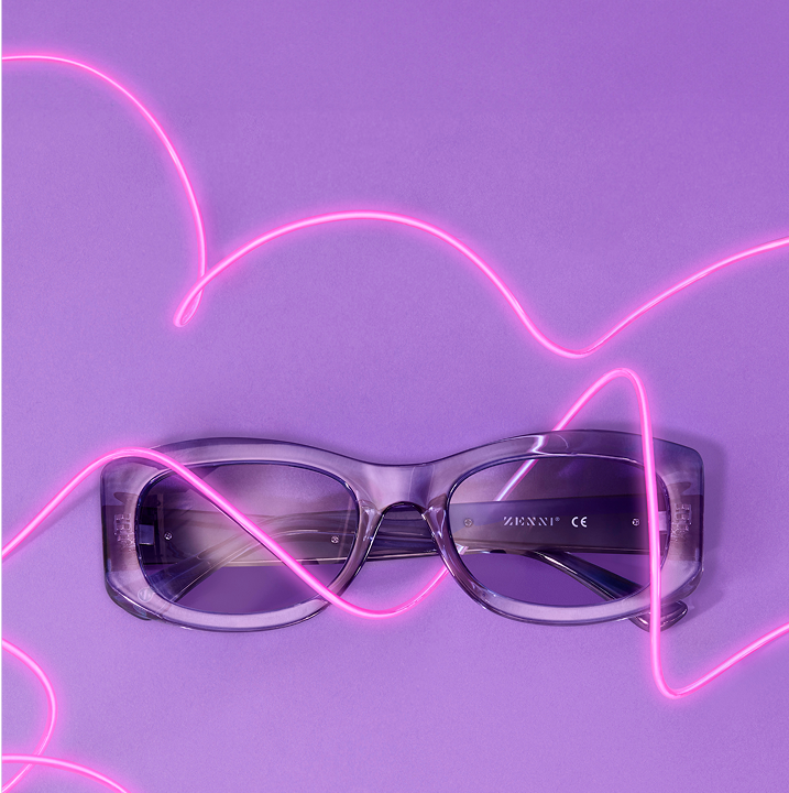 Purple Zenni Summer Brights frames on a purple background with pink neon light accents.