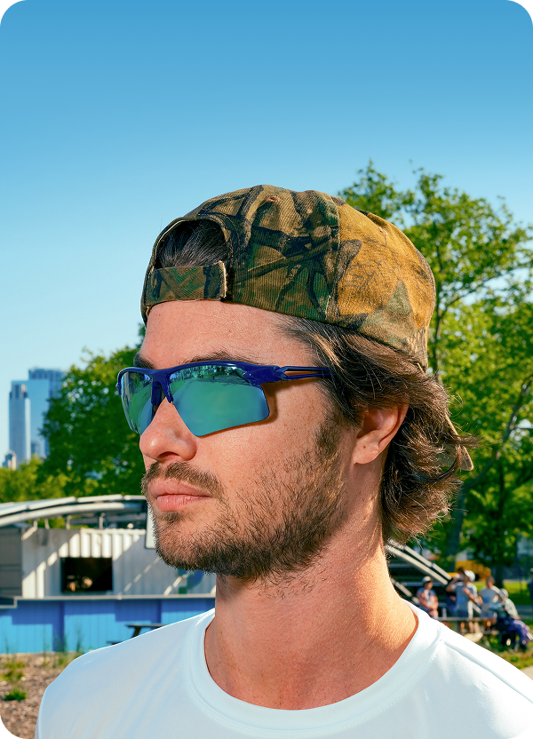 Chase Stokes wearing mirrored Zunnies sunglasses, running outdoors with the city skyline in the background.