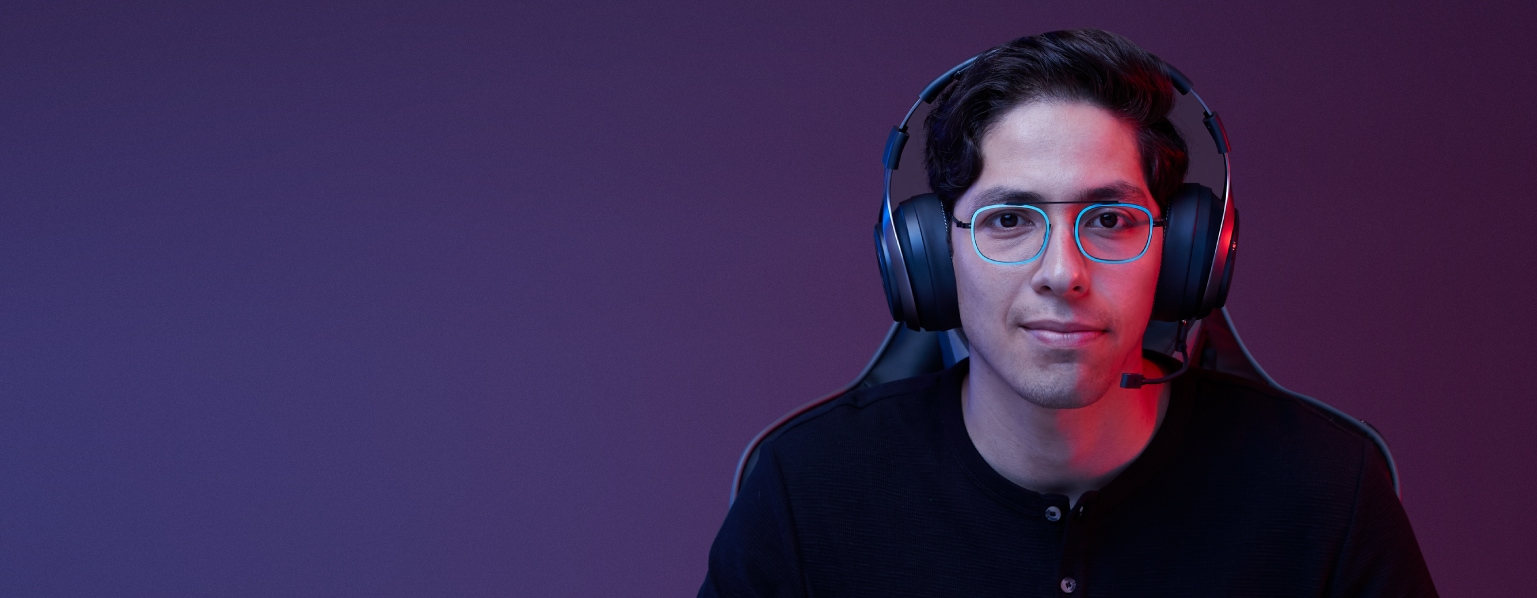 Gamer guy with short brown hair wearing bridgeless rectangle glasses #7818116 with teal metallic rims, gaming headset, and black Henley shirt.