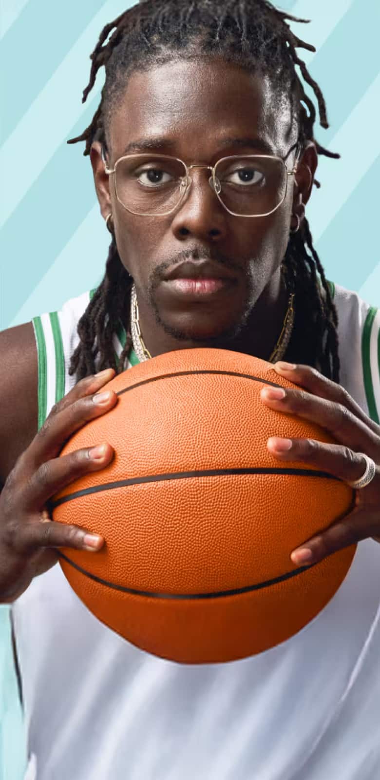 Jrue Holiday wears gold “Hendrix” optical glasses from his Zenni collection, dressed in an NBA Boston Celtics jersey, holding a basketball against a teal-patterned backdrop.
