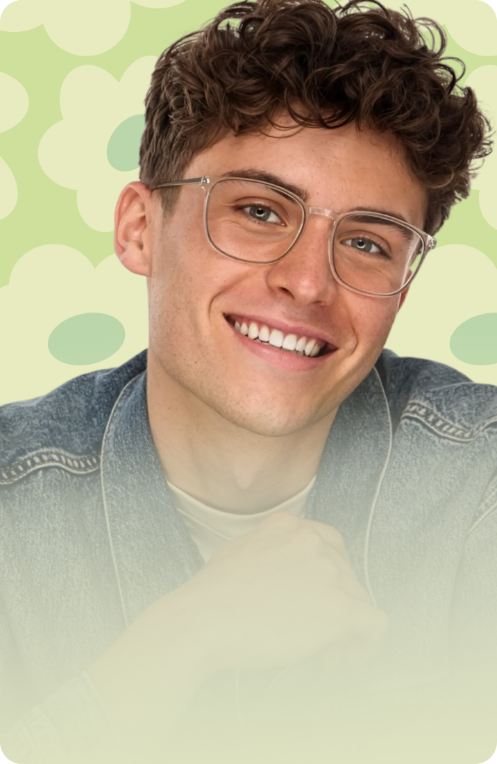 A smiling man with curly brown hair wearing translucent grey rectangular glasses and a denim jacket against a pale green background with large flower illustrations.