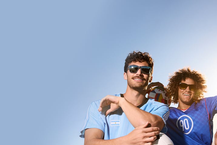 Aficionado al fútbol con Lentes de Sol Zenni, sonriendo con una bufanda azul detrás.
