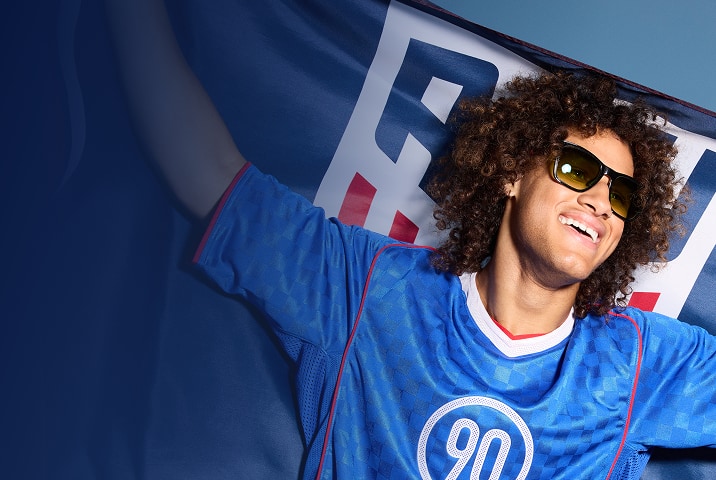 Soccer fan wearing Zenni sunglasses, smiling with a blue scarf behind him.