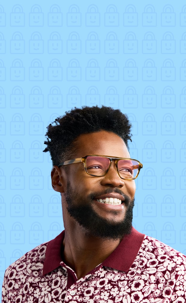 Man wearing glasses with Zenni ID Guard pink-sheen lenses, smiling and looking off camera with a patterned shirt against a light blue background.