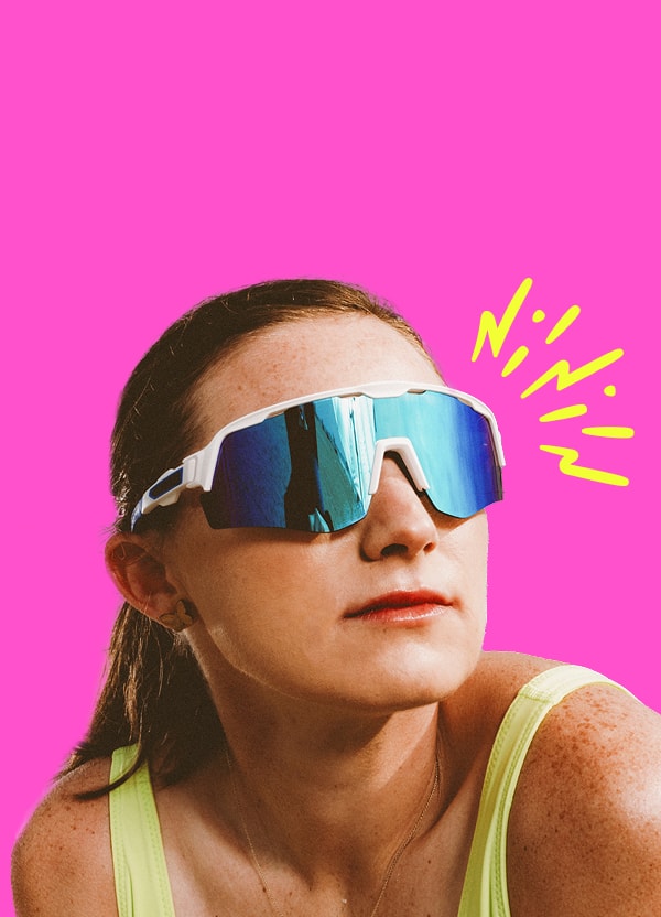 Pro volleyball player Kristen Nuss wearing reflective blue Zunnies sunglasses and a yellow tank, looking upward.