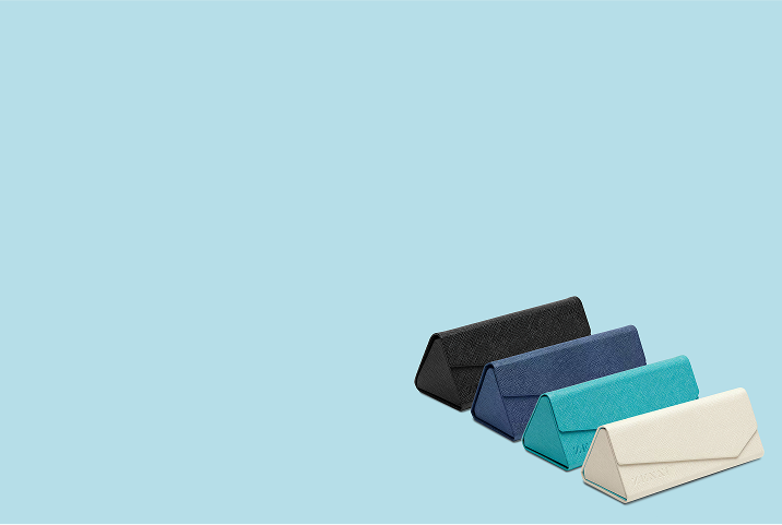Four Zenni triangular foldable eyeglass cases in black, navy, teal, and cream are lined up on a light blue background.
