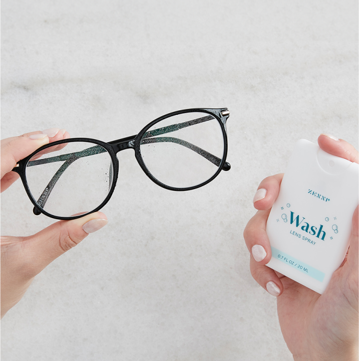Image of a hand holding a pair of Zenni glasses, and another hand holding Zenni's lens spray.