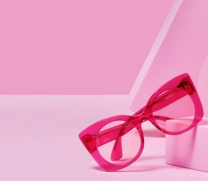 Image of translucent pink cat-eye glasses displaying on baby pink block with the same color background.