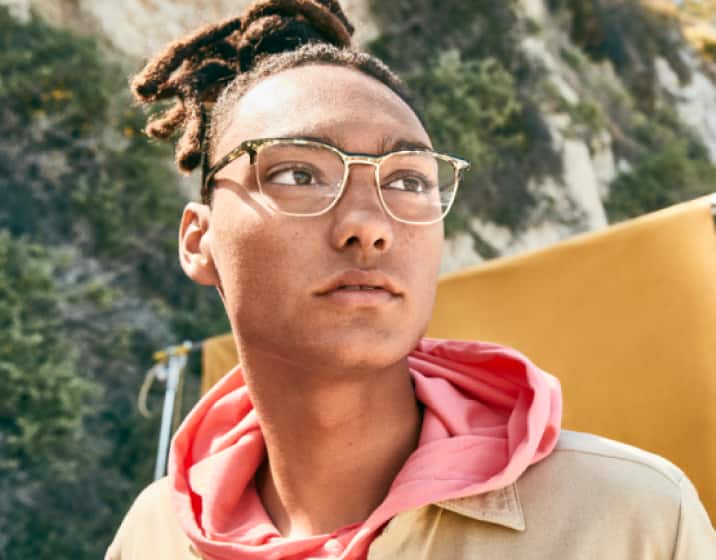 A young man is wearing his clear Blokz blue light glasses while hiking in the sun.
