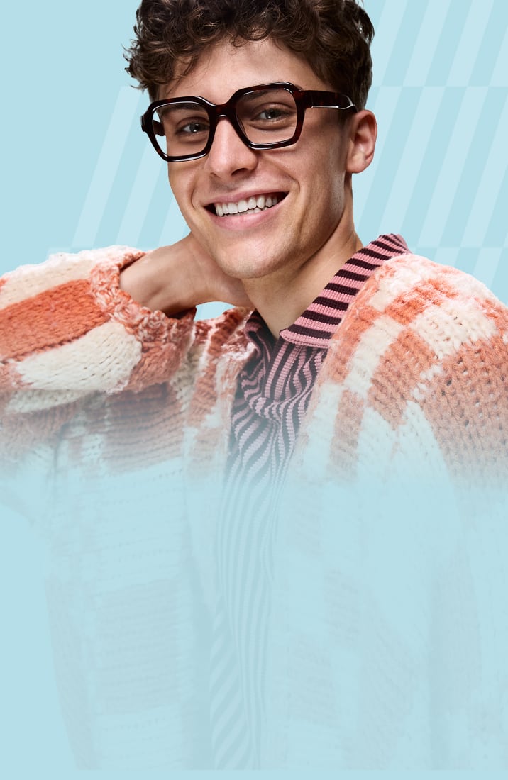 Man in chunky Zenni glasses and cozy orange sweater, smiling against a light blue background