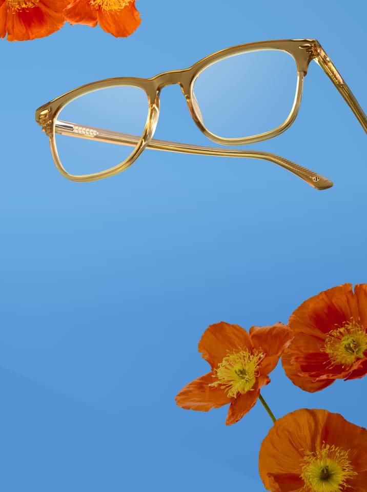 Translucent honey-colored rectangular eyeglasses floating against a bright blue background with vibrant orange poppy flowers.