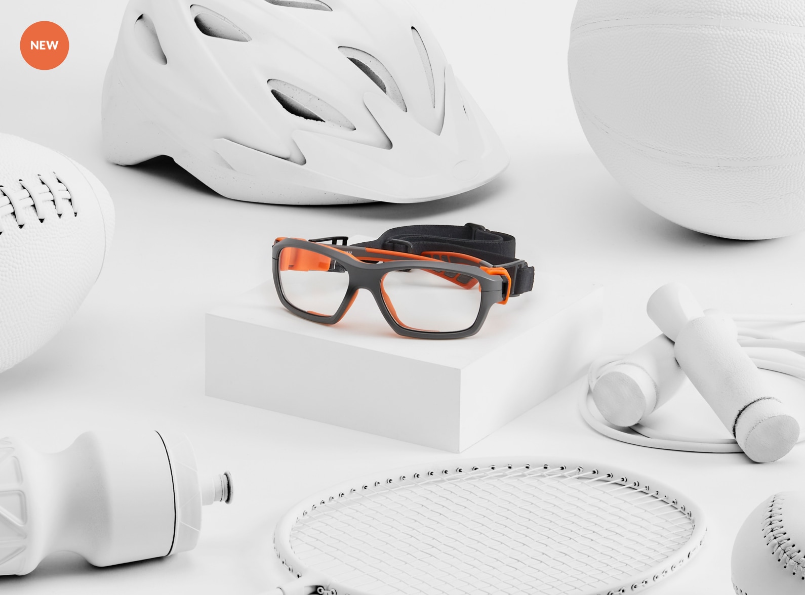 Gray and orange protective sports glasses surrounded by white sports equipment including a helmet and racket.