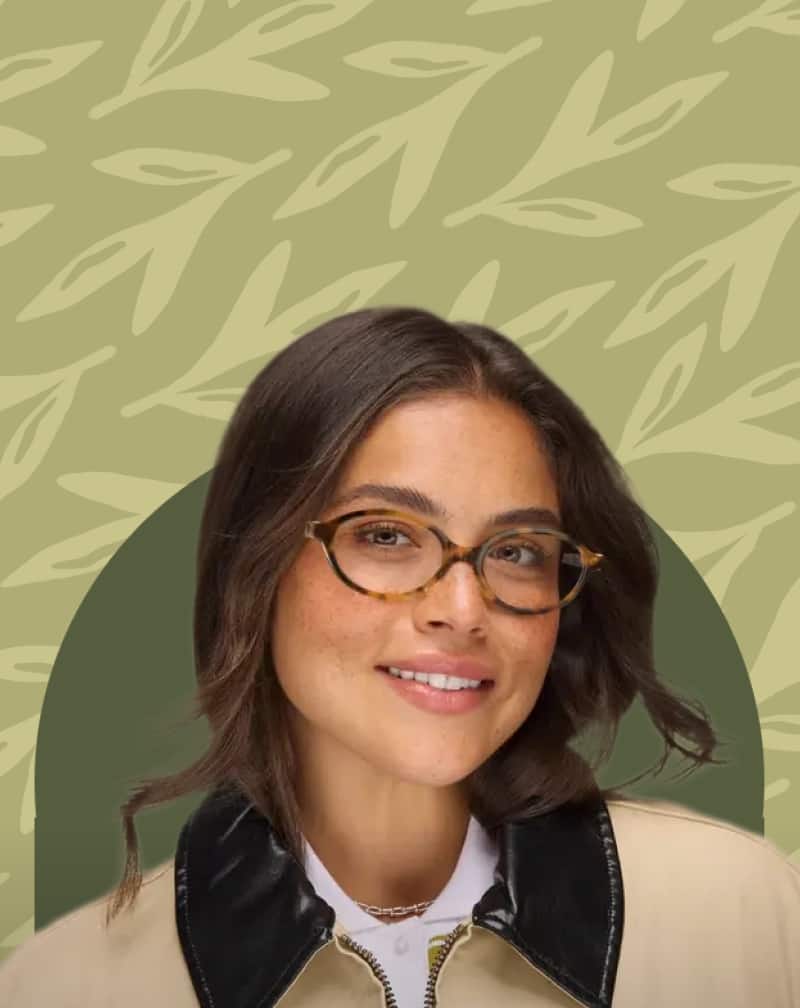 Smiling woman wearing tortoiseshell oval eyeglasses against a sage green background with leaf pattern illustrations.