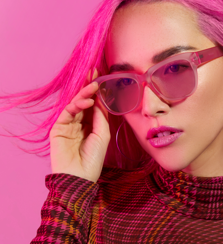 Woman with pink hair wearing pink plastic frames with rose tinted lenses.