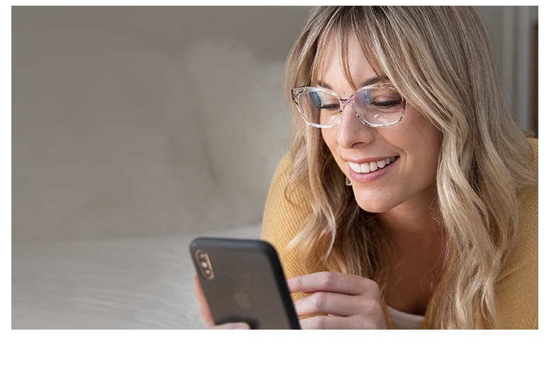Woman with blond hair uses her iPhone while wearing translucent floral cat-eye glasses # 2018723.