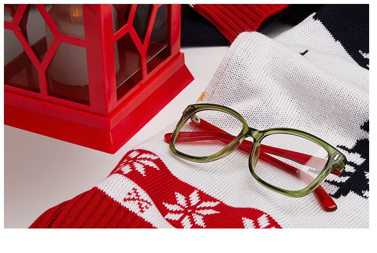 Translucent green square glasses with red temple arms #126224 on top of knit scarf with winter motif next to red lantern.