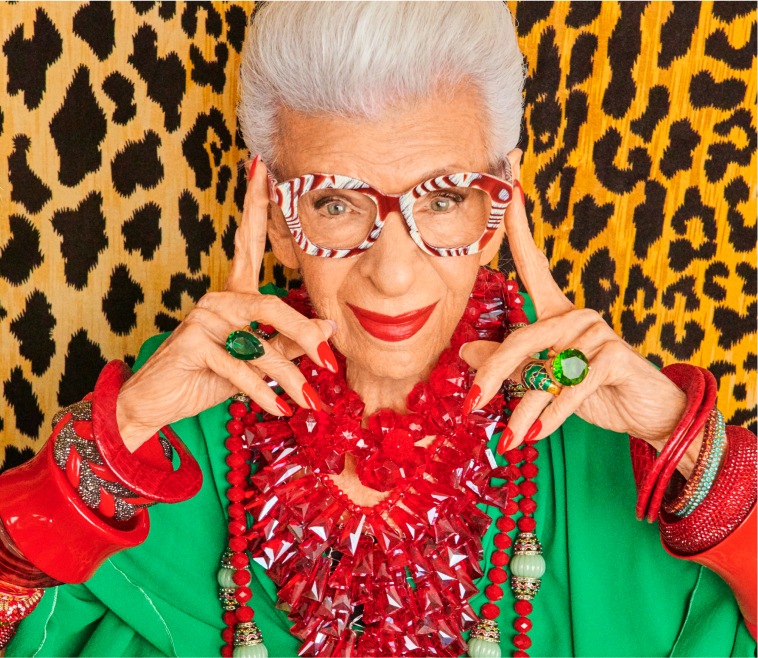 Image of Iris Apfel wearing Zenni smashing! cat-eye glasses #4452815. She is touching the outer edge of the frames with her fingers, standing in front of a leopard print wall.