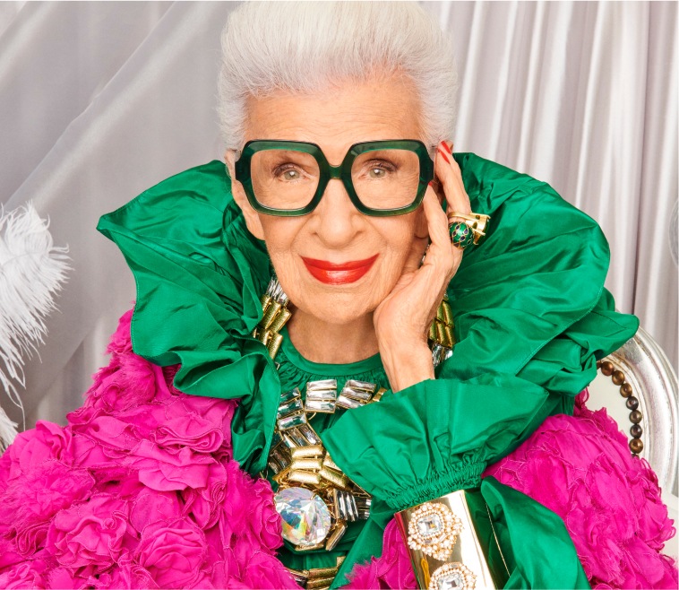 Image of Iris Apfel wearing Zenni Good to be square glasses #4452924. She is wearing a bright green ruched collar and is in front of a silver wall.