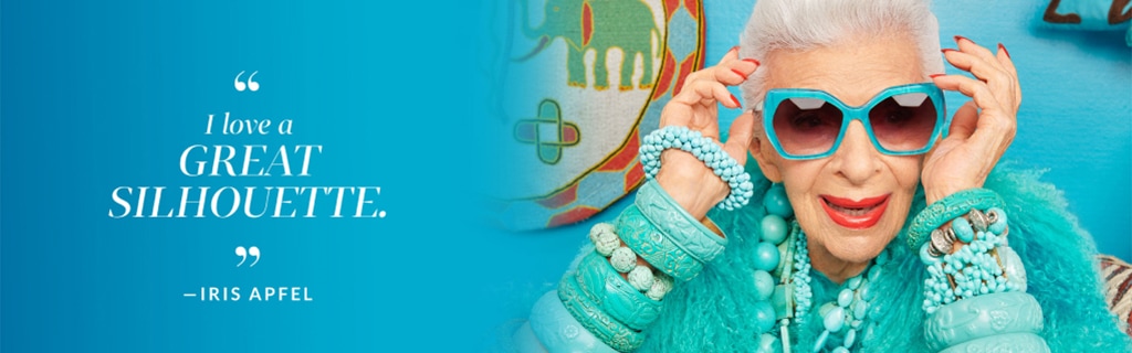 ‘I love a great silhouette.’ -Iris Apfel. Image of Iris Apfel wearing Zenni Mulholland sunglasses #112624 against a blue background with ethnic art behind her.