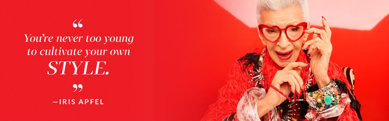 ‘You’re never too young to cultivate your own style.’ -Iris Apfel. Image of Iris Apfel wearing Zenni geometric heart-shaped glasses #2029918, against a red background with a yellow monkey toy behind her.