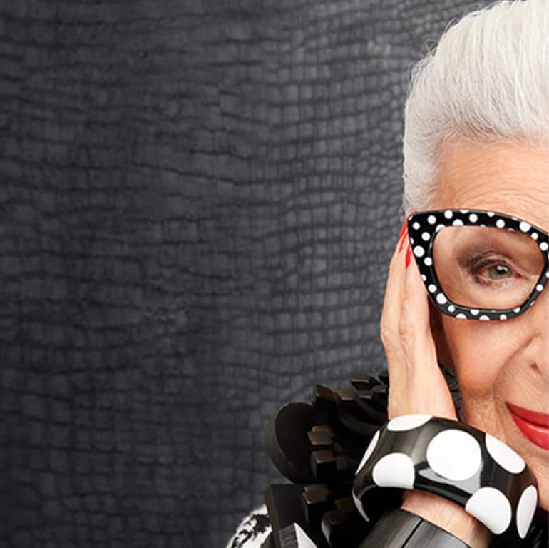 Image of Iris Apfel wearing Zenni black and white cat-eye glasses #2033421 against a black textured background.