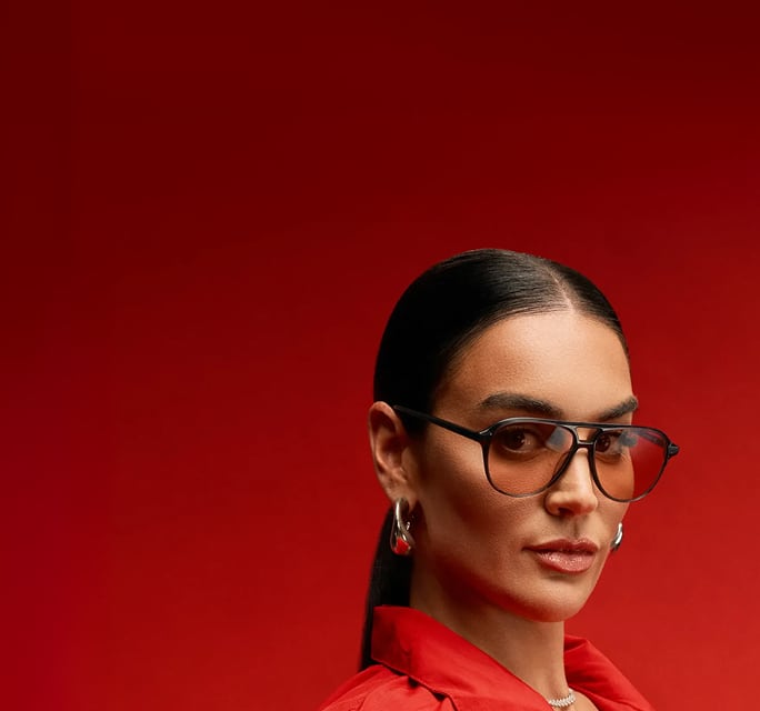 Claire Kittle sobre un fondo rojo usando lentes de aviador de carey marca Zenni de la colección The Kittles.