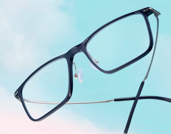 Black square glasses floating on a background of blue sky with fluffy clouds.