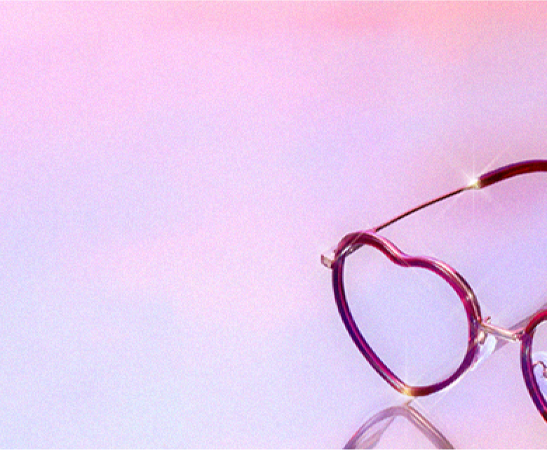 A pair of heart-shaped glasses on a pastel purple and pastel pink background.