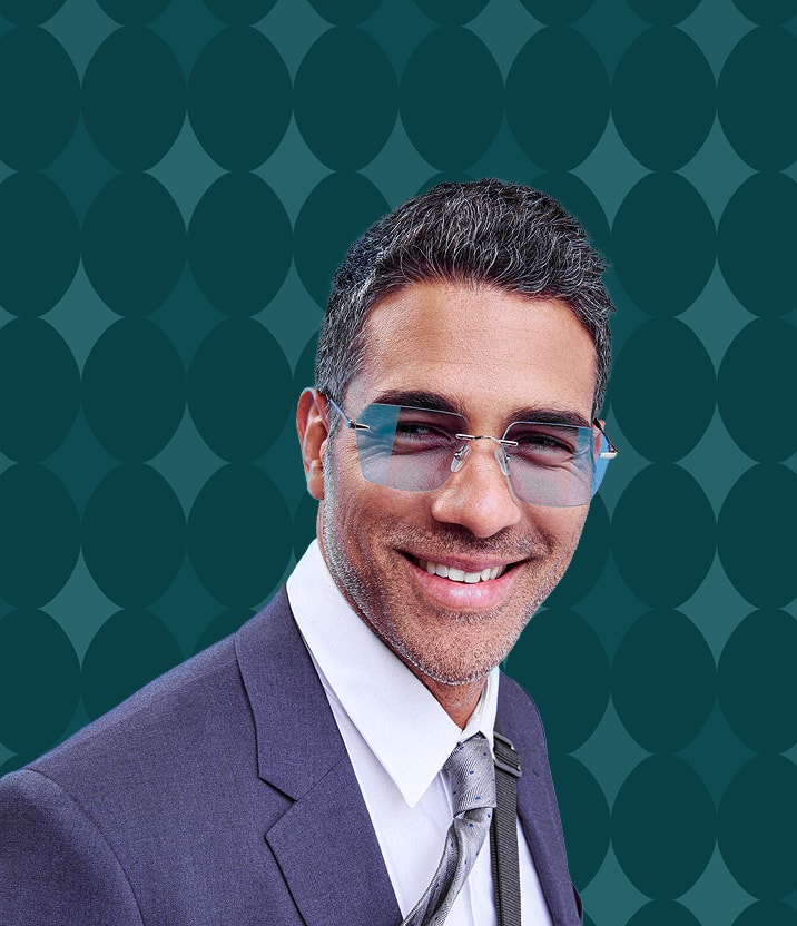 A man with salt and pepper hair wearing rimless square glasses with a blue tint, on a dark teal background with an oval motif.