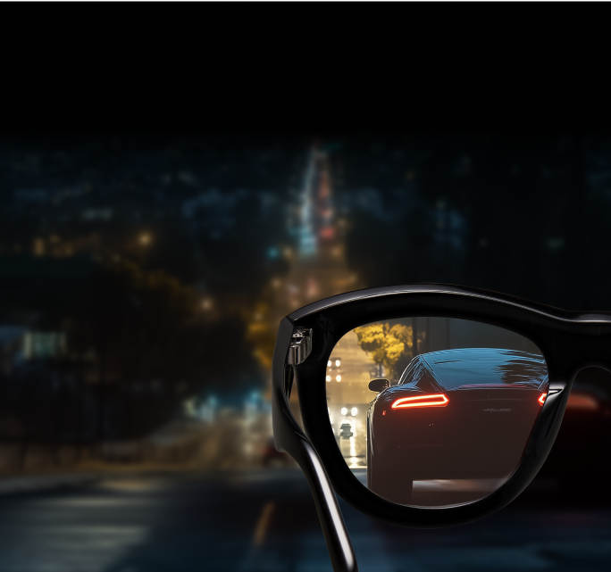Cat-eye black glasses with nearly clear night driving lenses, reflecting a street at night where the LED tail lights are crisp with almost no glare.