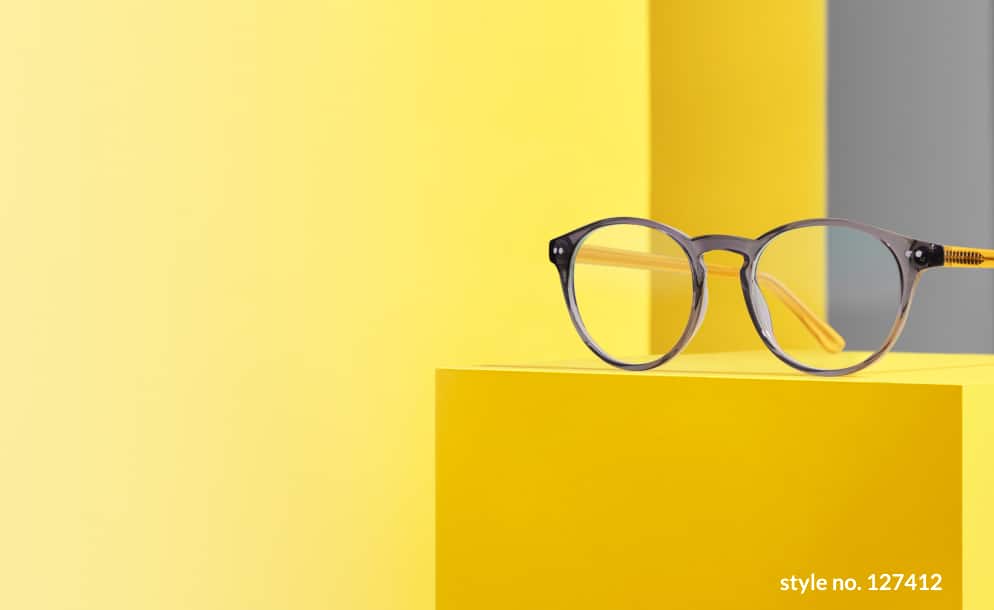 Image of a pair of Zenni round glasses #127412 on a yellow platform, against a yellow and grey background.