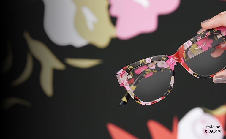 Image of a hand holding Zenni square glasses #2026729, with a floral background.
