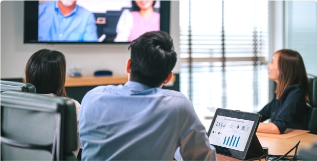 Image of 3 people sitting at an office desk watching a zoom call, wearing Zenni glasses..