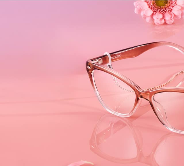Red gradient cat-eye glasses with silver eyeglass chains on a pink background.