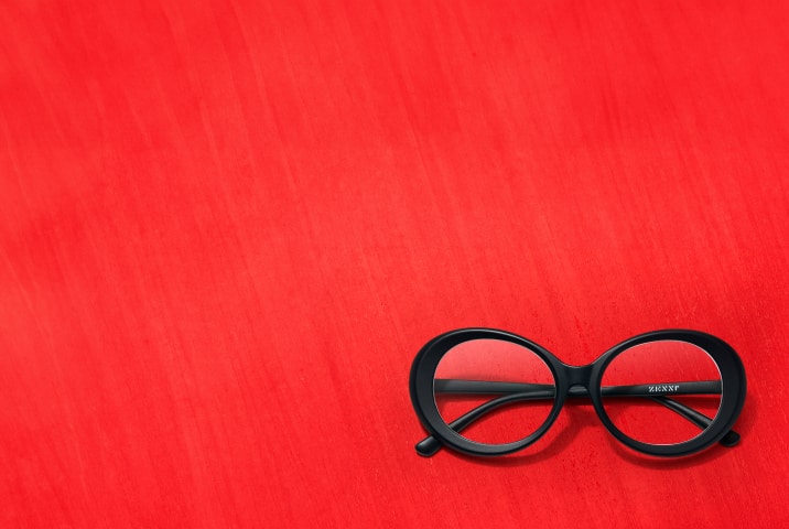 Black round oversized glasses on a bright red background.