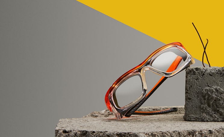 Image of Zenni safety glasses #749618 on a concrete slab, on a gray and yellow background.