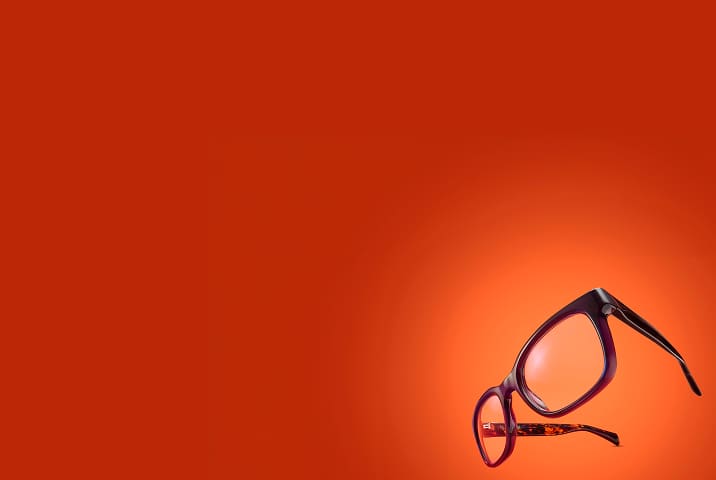 A pair of rectangular eyeglasses with deep purple frames and tortoiseshell-patterned arms is displayed against a vibrant orange background.