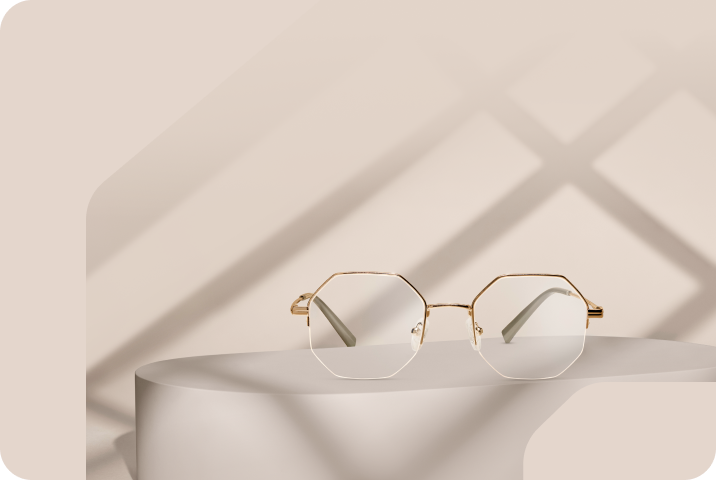 Gold geometric half-rim metal Zenni glasses with clear lenses on a beige pedestal.