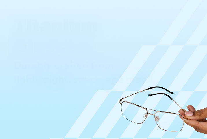A hand holding a pair of silver rectangle titanium glasses with black temple tips on a light blue background.