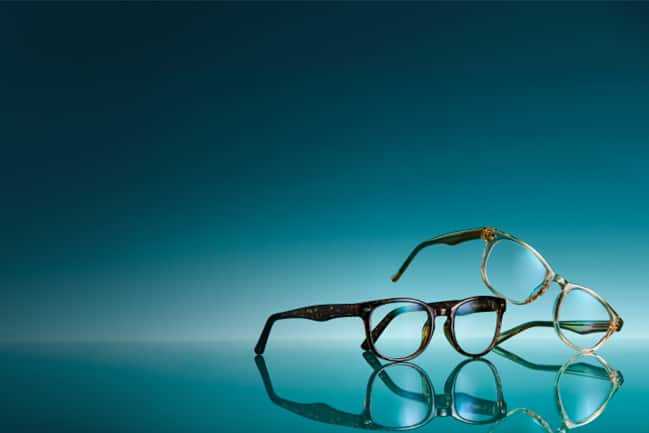 Brown background with 2 prescription glasses: tortoiseshell round glasses and brown rectangle glasses.