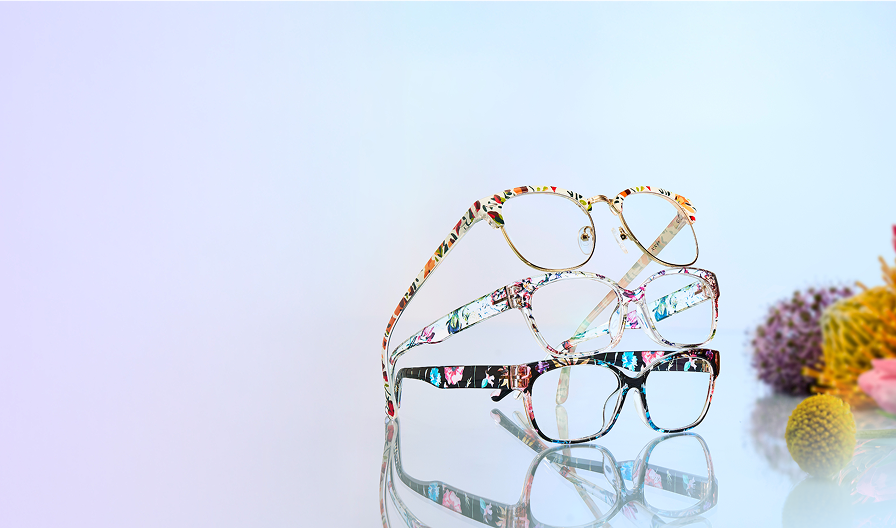 Three floral-patterned eyeglasses style no. 2018723, 1912029, 2018716, stacked diagonally on a gradient background with flowers on the side.