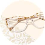 Zenni cat-eye glasses #7823039 on a cream-colored background with white floral print accents.