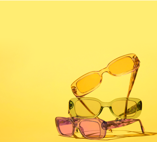 Three pairs of purple, green, and beige rectangle sunglasses on a yellow background.