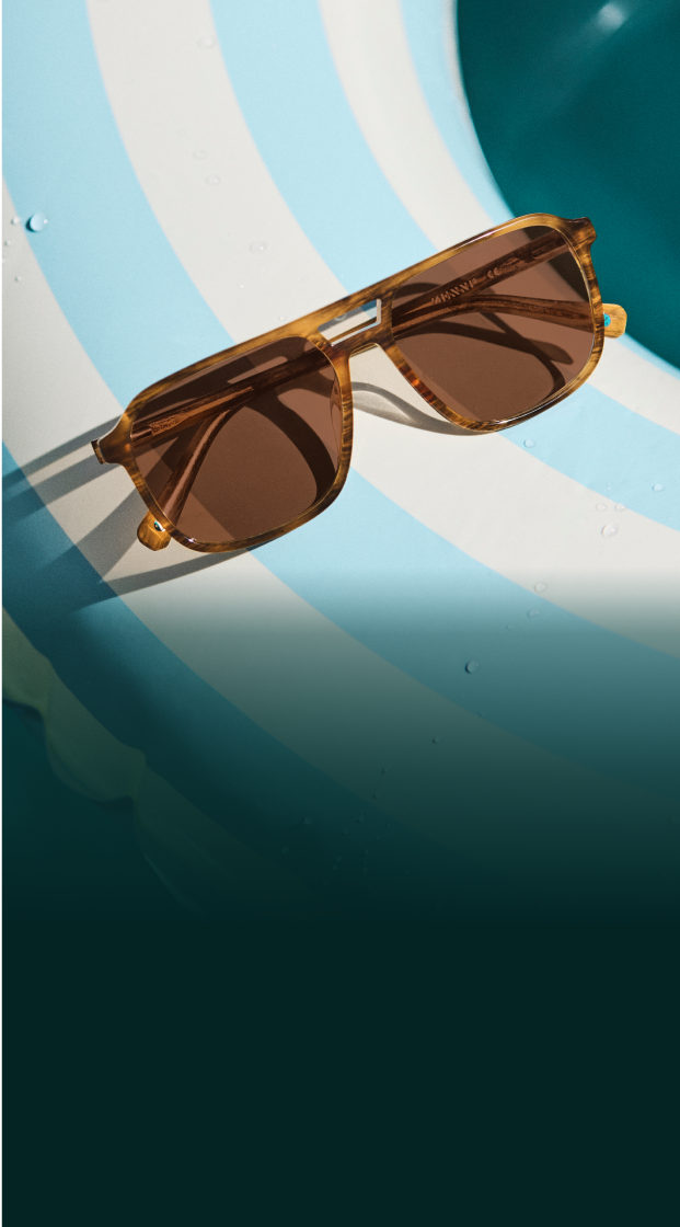Tortoiseshell aviator sunglasses resting on a blue and white striped inner tube floating in a pool.
