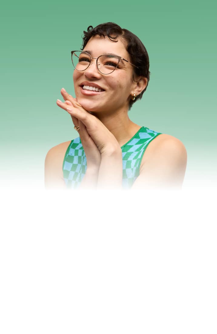 A smiling woman with short curly hair wearing cat-eye style “Page” Timo x Zenni glasses against a light green background.